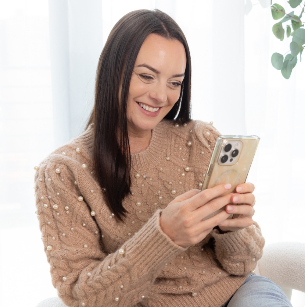 Amber Olson Rourke smiling while looking down at her phone.